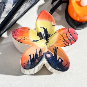 Close-up of Halloween flower hair claw clip with witch and bat prints on resin