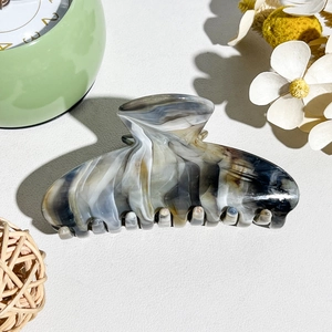 Detailed close-up of marble pattern acetate hair claw clip with golden metal spring
