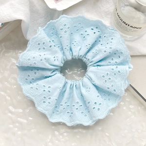 Detail of light blue lace embroidery scrunchie with hollow floral patterns and wavy edges
