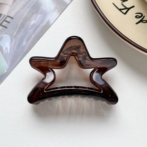Détail d'une pince à cheveux étoile marron translucide avec ressort métallique apparent