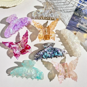 Flat lay of iridescent acetate hair claws in butterfly and shell shapes with pearly finish