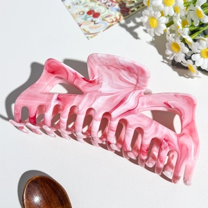 Dettaglio macro della trama marmorizzata rosa e bianca su una grande molletta per capelli