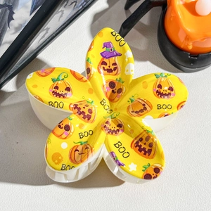 Macro shot of Halloween flower hair claw clip with pumpkin prints and BOO lettering detail
