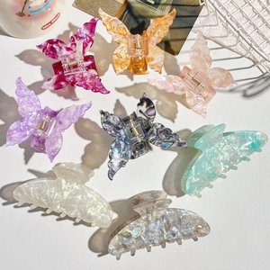 Flat lay of colorful marble textured butterfly hair claws and shark clips on a white surface