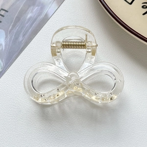 Détail d'une pince à cheveux transparente en forme de nœud avec ressort doré