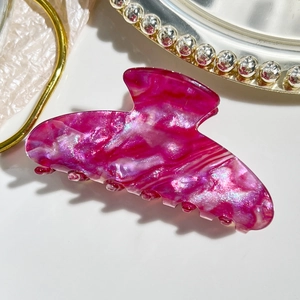 Macro detail of glossy magenta marble finish on large hair claw clip with star glitter