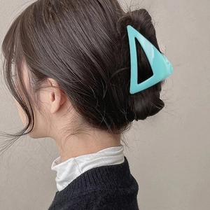 Pince à cheveux triangle creux bleu clair pour chignon femme montrée sur cheveux foncés