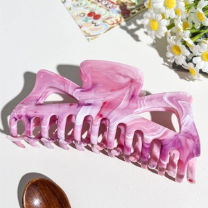 Dettaglio della grande pinza per capelli in marmo rosa per acconciature folte