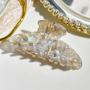Macro detail of elegant pearlescent acetate hair claw with golden tray accent