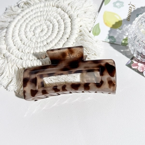 Detail of leopard print hair claw clip on white leather with elegant lemon decor