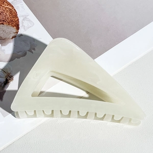Vue détaillée d'une pince à cheveux triangulaire crème avec un design ajouré élégant