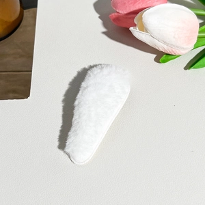 Detailed macro view of soft white plush fabric texture on a stylish hair clip