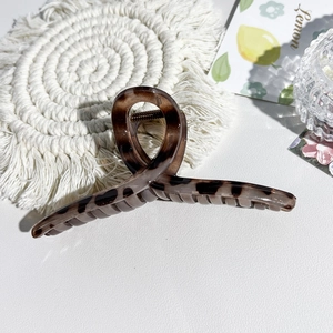 Macro view of large leopard print hair claw clip on a stylish white textured table