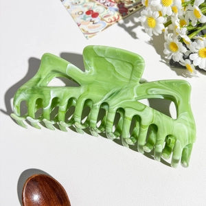 Dettaglio della grande molletta per capelli in marmo verde con elegante trama in acetato