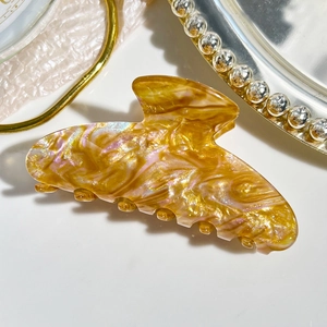 Detailed close-up of marble acetate hair claw clip with colorful iridescent glow