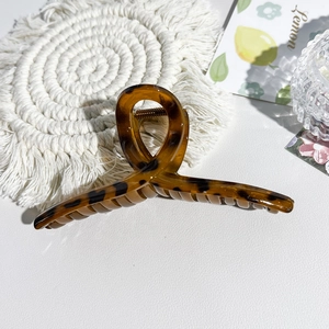 Macro shot of large leopard print hair claw clip with metal spring on a woven mat