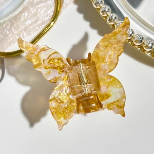 Detailed butterfly hair claw clip with amber marble texture and subtle purple shimmer