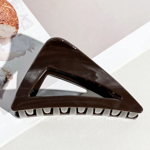 Détail d'une grande pince à cheveux triangulaire marron café avec finition brillante