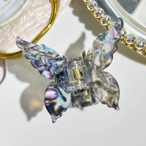 Detailed close-up of marble purple butterfly hair claw clip with golden metal spring