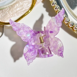 Detail of purple acetate butterfly hair claw clip with glitter finish and gold spring