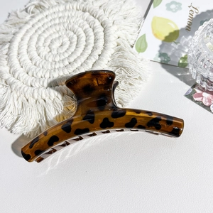Close-up of leopard print hair claw clip on a white textured background with lemon card
