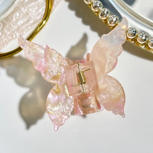 Detail of pink gradient butterfly hair claw clip with golden glitter and sturdy metal spring