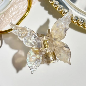 Macro shot of iridescent butterfly hair claw clip with premium acetate texture and gold spring