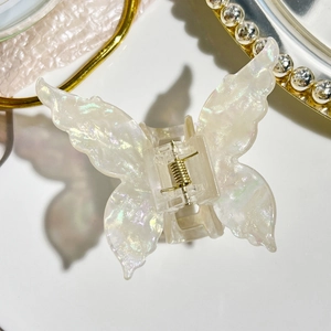 Detail of butterfly iridescent acetate hair claw clip with golden metal spring and pearl finish