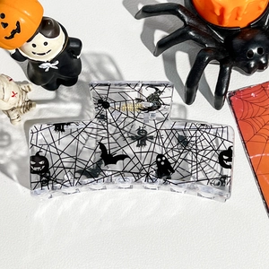 Macro shot of Halloween pumpkin and bat prints on a transparent square hair claw clip