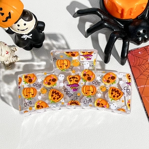 Detail of Halloween hair claw clip with pumpkin and ghost prints on a festive background