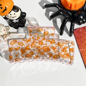 Detail of transparent Halloween hair claw clip with orange pumpkin and ghost print