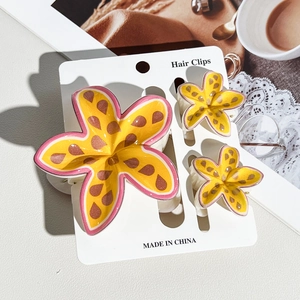 Detailed set of three yellow tropical plumeria flower hair clips on a display card