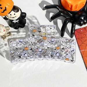 Macro shot of Halloween claw clip with ghost and pumpkin prints on leather background