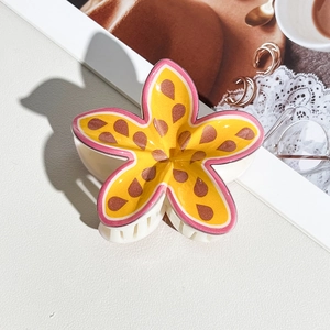Macro view of a cute yellow and pink floral hair claw clip on a stylish table background
