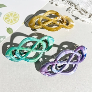 Detailed view of three Celtic knot hair clips with marble texture in amber, green and purple