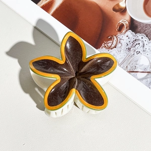 Detail of tropical frangipani flower hair claw clip with colorful resin petals and white teeth