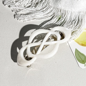 Detailed view of cream resin infinity spring hair clip on elegant white textured surface