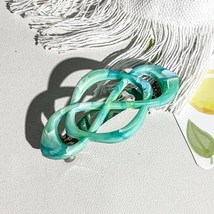 Macro detail of marble-textured Celtic knot hair clip with green and blue acetate finish