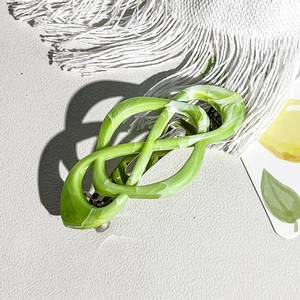 Macro view of green marble pattern hair clip with twisted infinity knot design