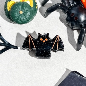 Macro view of bat-shaped Halloween hair clip with glitter finish and orange enamel details