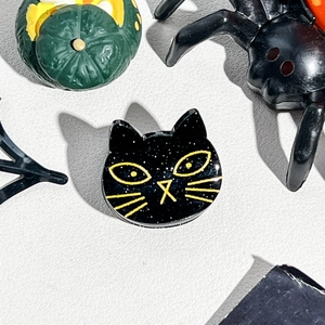 Close-up of black cat acrylic hair clip with glitter finish and yellow eye details