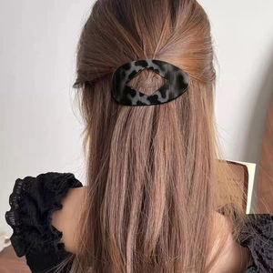 Flat oval leopard pattern hair claw with hollow diamond design on dark hair
