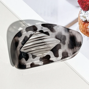Close-up of a large black and white marble pattern resin hair claw clip on white background