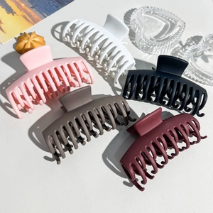 Detailed overhead view of five large matte shark hair clips in assorted colors for styling