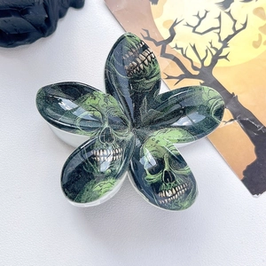 Detailed macro view of the green skull pattern on the glossy flower-shaped hair claw