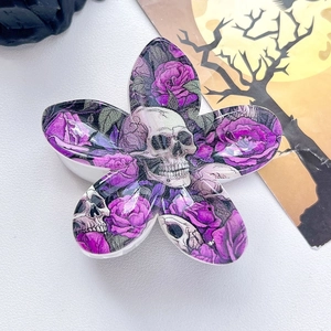 Detail of flower-shaped hair claw clip with vintage purple rose and skull patterns