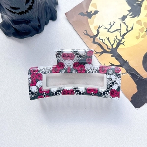 Detail of Halloween hair claw clip with skull and red rose pattern on white texture