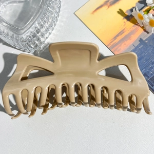 Detail view of large matte cream hair claw clip with strong grip teeth on white surface