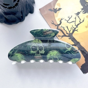 Detail of dark green Halloween hair claw clip with printed skull pattern and resin teeth