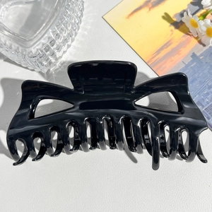 Close-up of 14cm large black matte shark hair clip with strong grip teeth on white texture